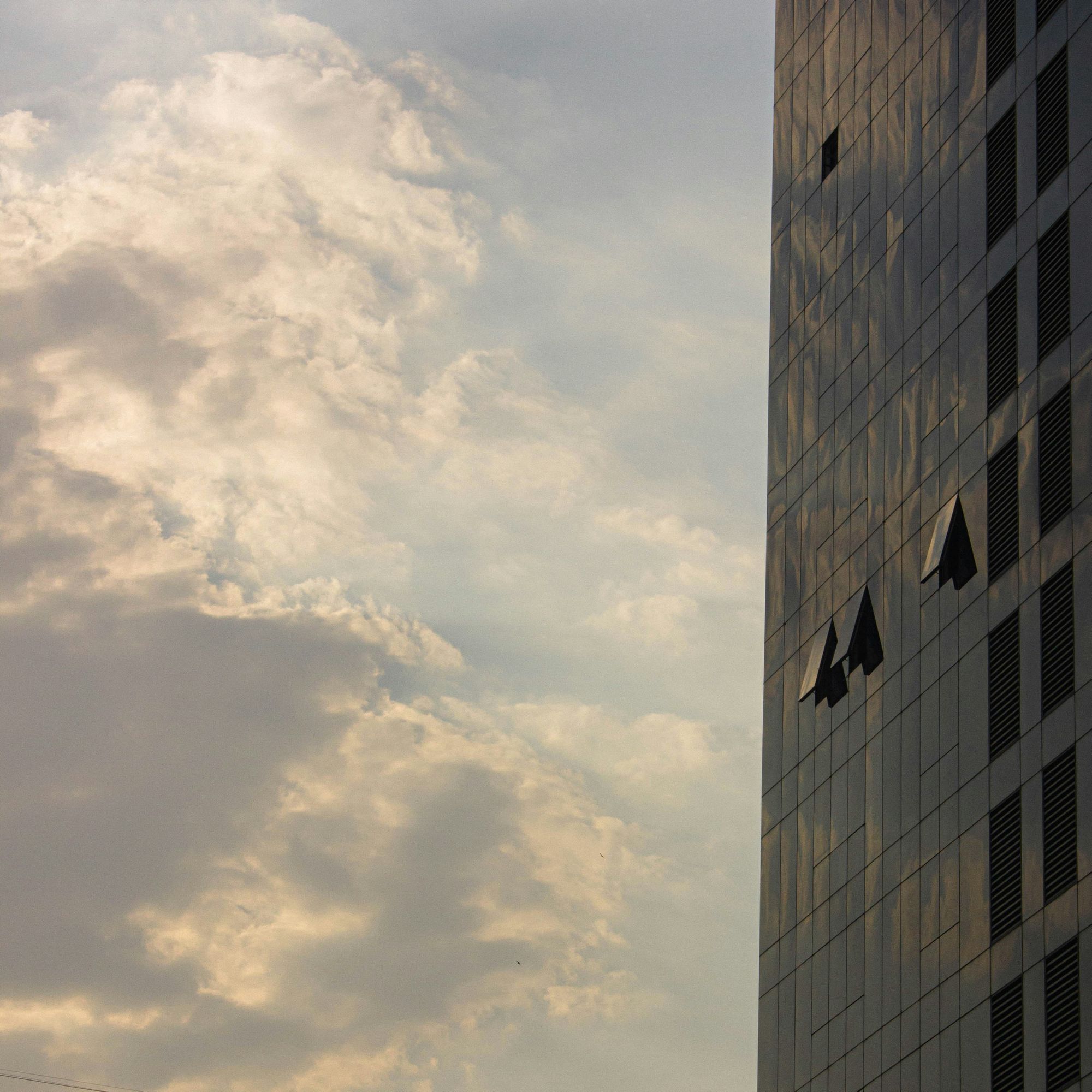 A modern corporate office tower against a bright sky